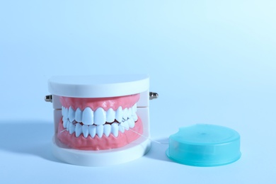 Photo of Typodont teeth and floss on color background, space for text. Dentist consultation