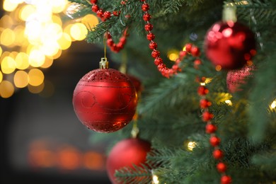 Photo of Closeup of red baubles hanging on Christmas tree, space for text. Bokeh effect