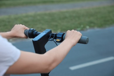 Photo of Woman with modern electric kick scooter outdoors, closeup