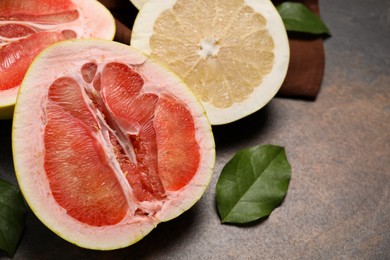 Photo of Fresh cut pomelo fruits with green leaves on dark table, closeup. Space for text