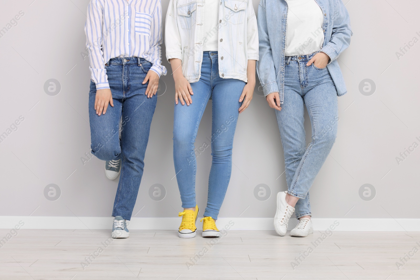 Photo of Women in stylish jeans near light grey wall indoors, closeup