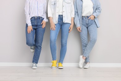 Photo of Women in stylish jeans near light grey wall indoors, closeup