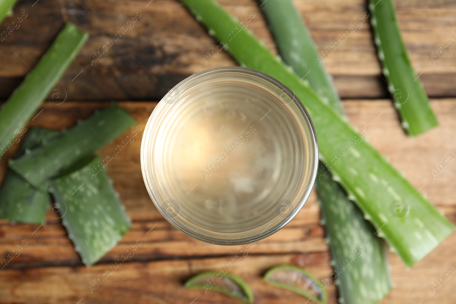 Photo of Fresh aloe drink in glass and leaves on wooden table, flat lay