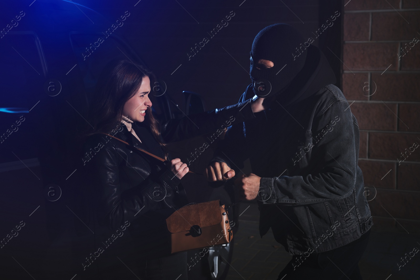 Photo of Woman fighting with thief while he trying to steal her bag outdoors at night. Self defense concept