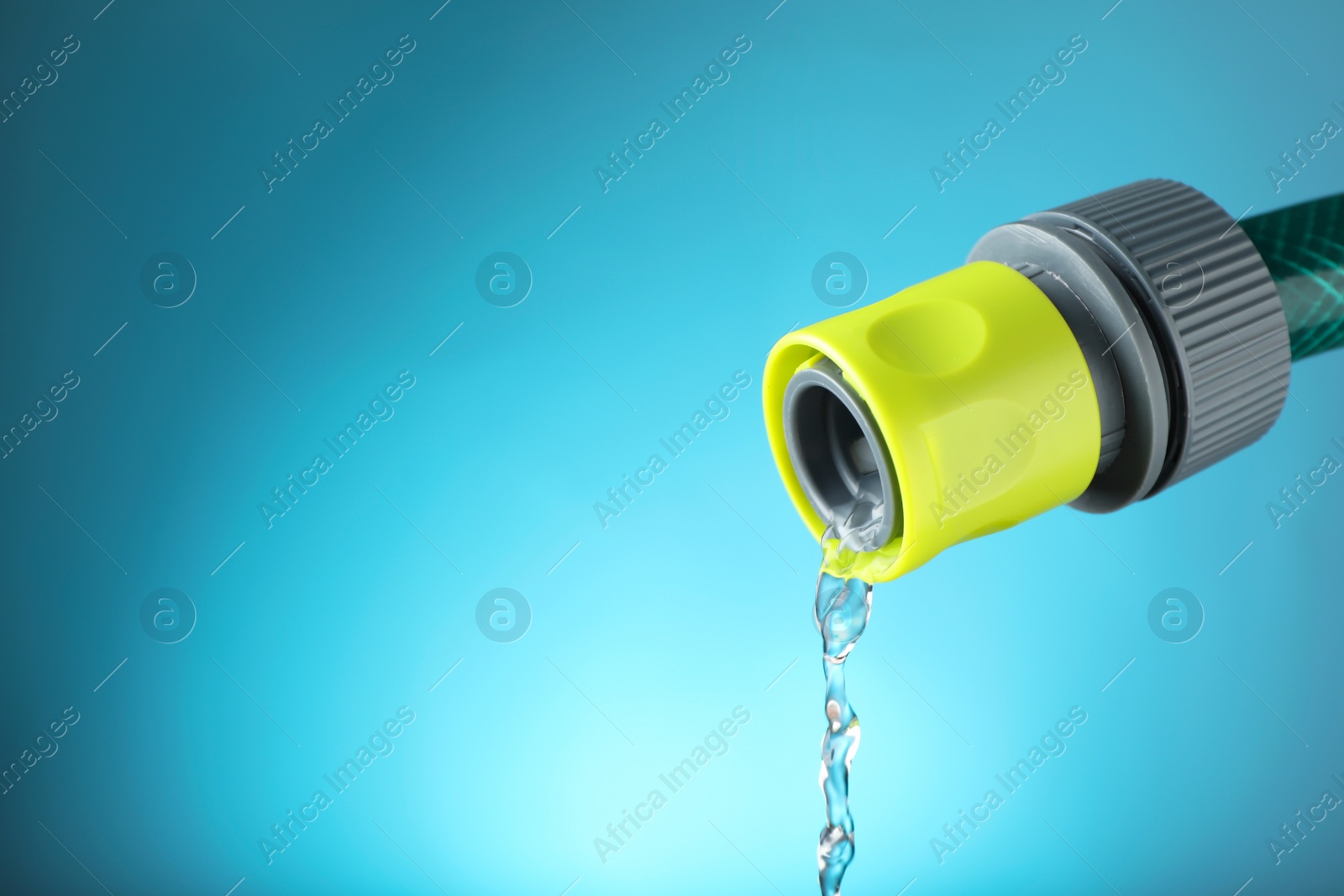 Photo of Water dripping from hose on light blue background, closeup. Space for text