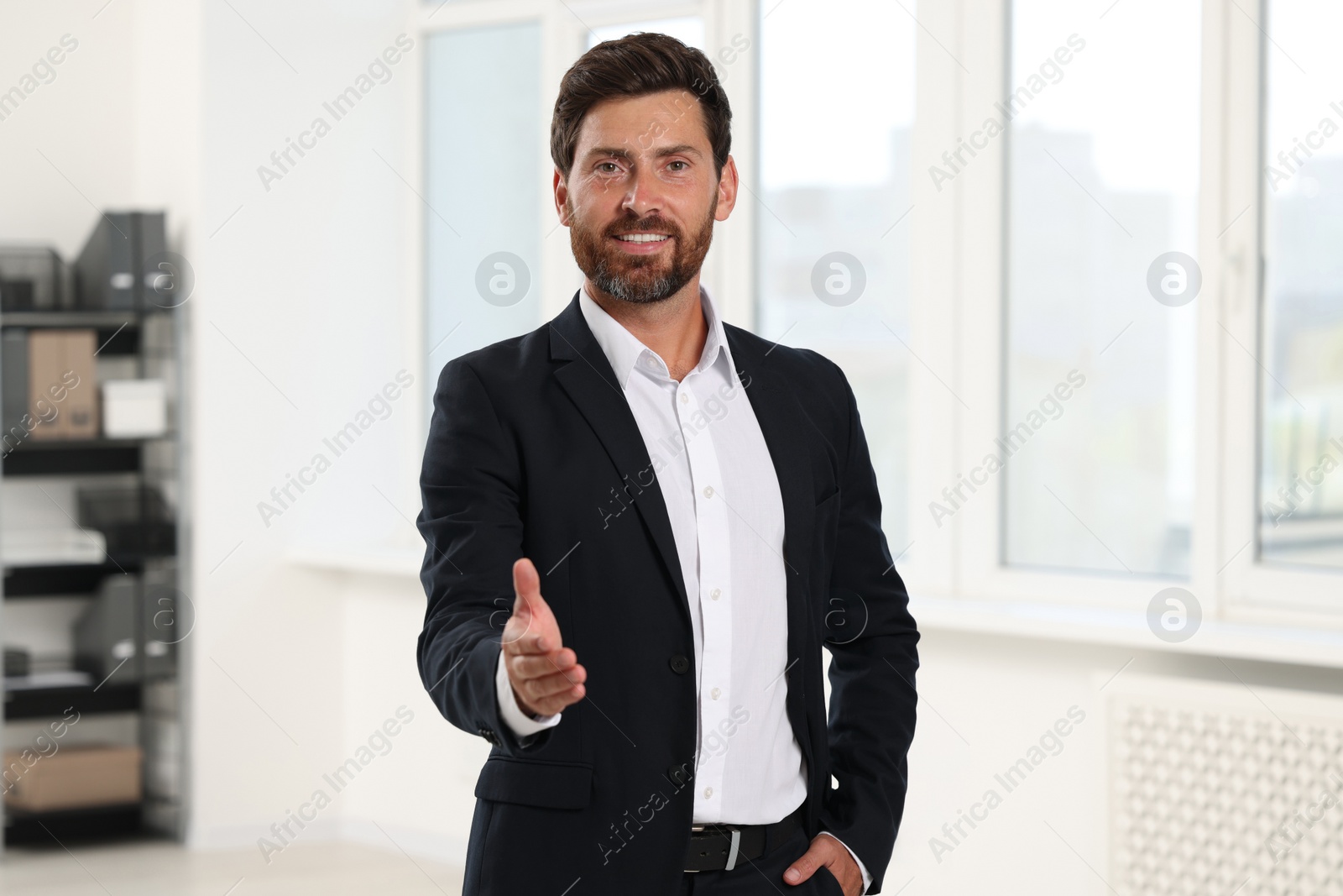 Photo of Happy man welcoming and offering handshake in office