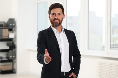 Happy man welcoming and offering handshake in office