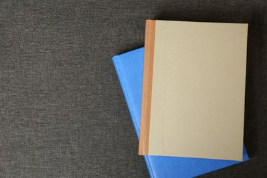 Photo of Hardcover books on grey fabric, top view. Space for text