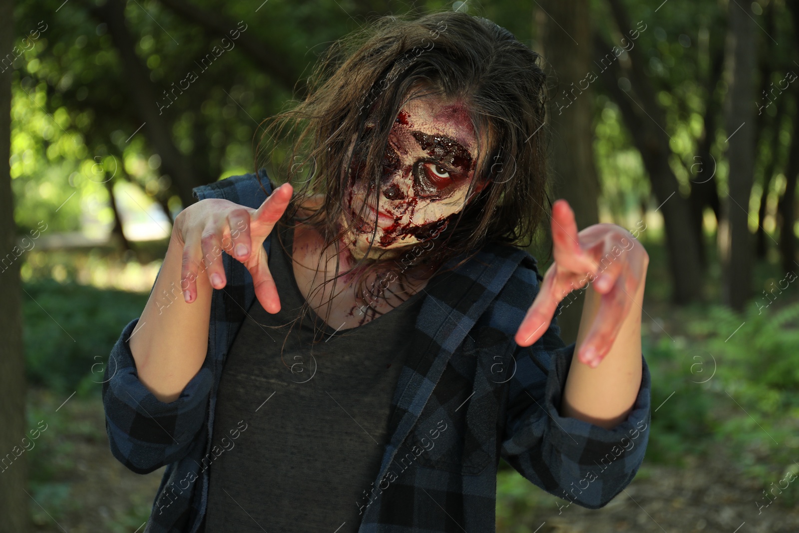 Photo of Scary zombie with bloody face outdoors. Halloween monster