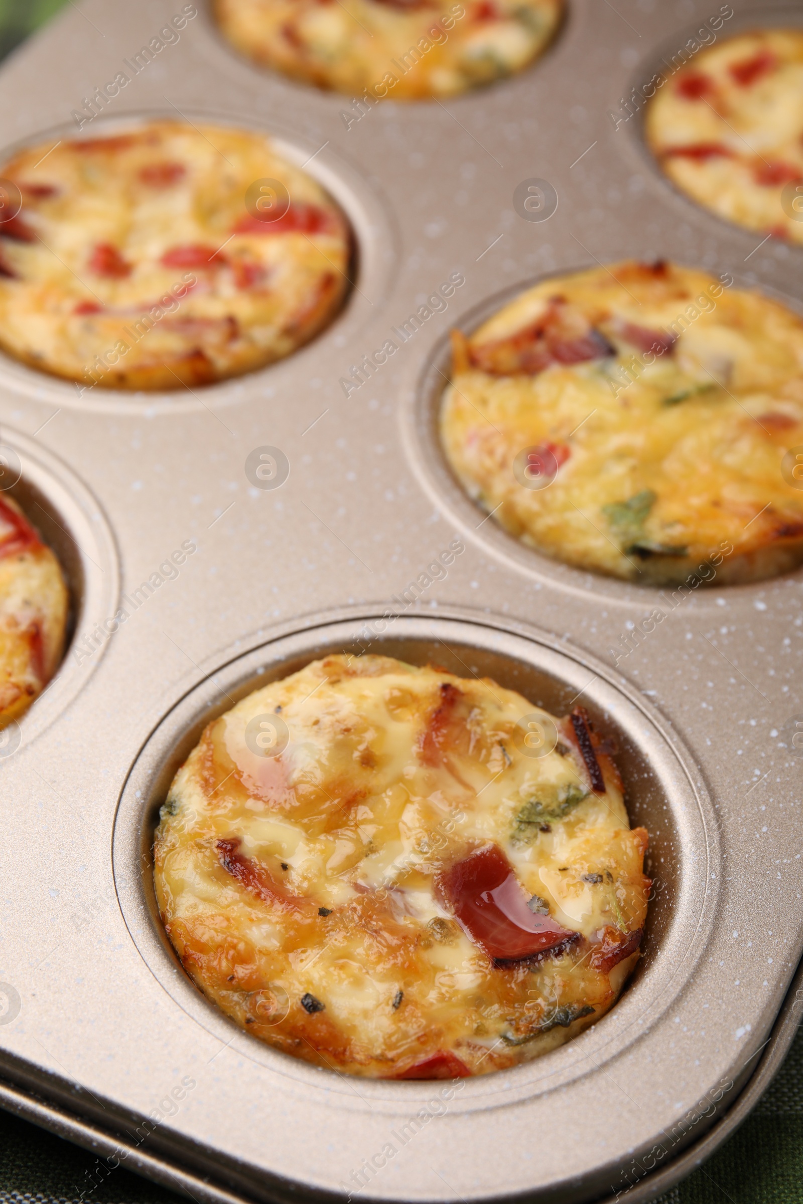 Photo of Freshly baked bacon and egg muffins with cheese in tin, closeup