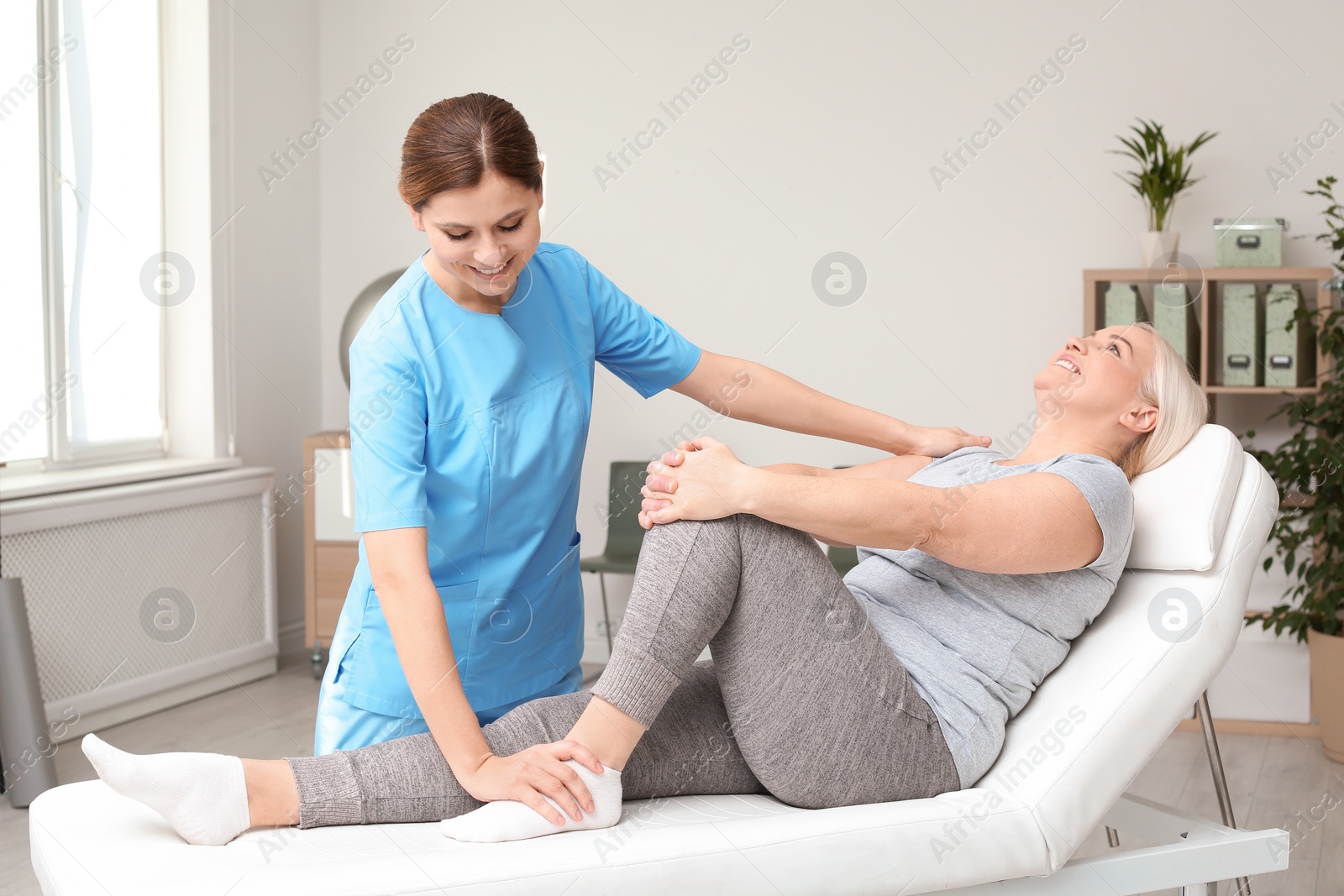 Photo of Physiotherapist working with patient in clinic. Rehabilitation therapy