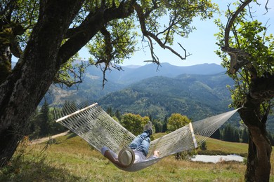 Young man resting in hammock outdoors on sunny day