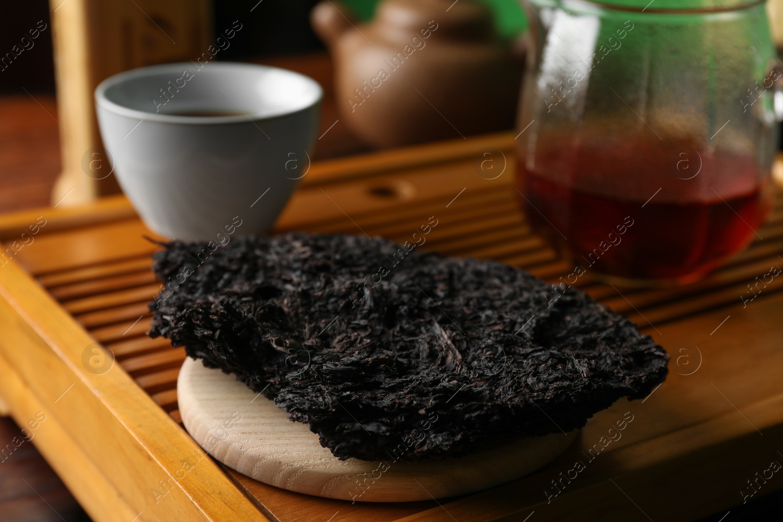 Photo of Broken disc shaped pu-erh tea on wooden tray, closeup