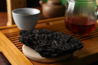 Photo of Broken disc shaped pu-erh tea on wooden tray, closeup