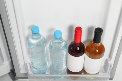 Bottles of water and wine on shelf in refrigerator