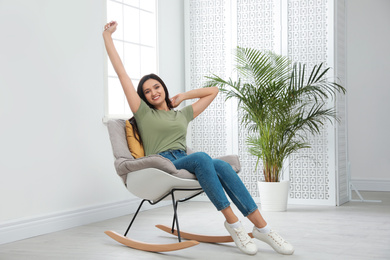 Photo of Young woman relaxing in rocking chair at home