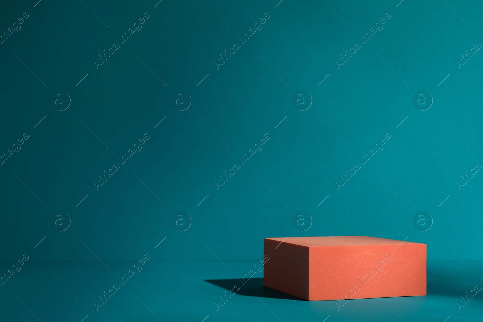 Photo of Orange stand on teal background, space for text. Stylish presentation for product