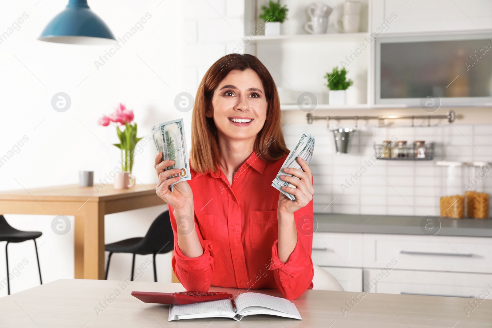 Photo of Smiling woman counting money at table indoors