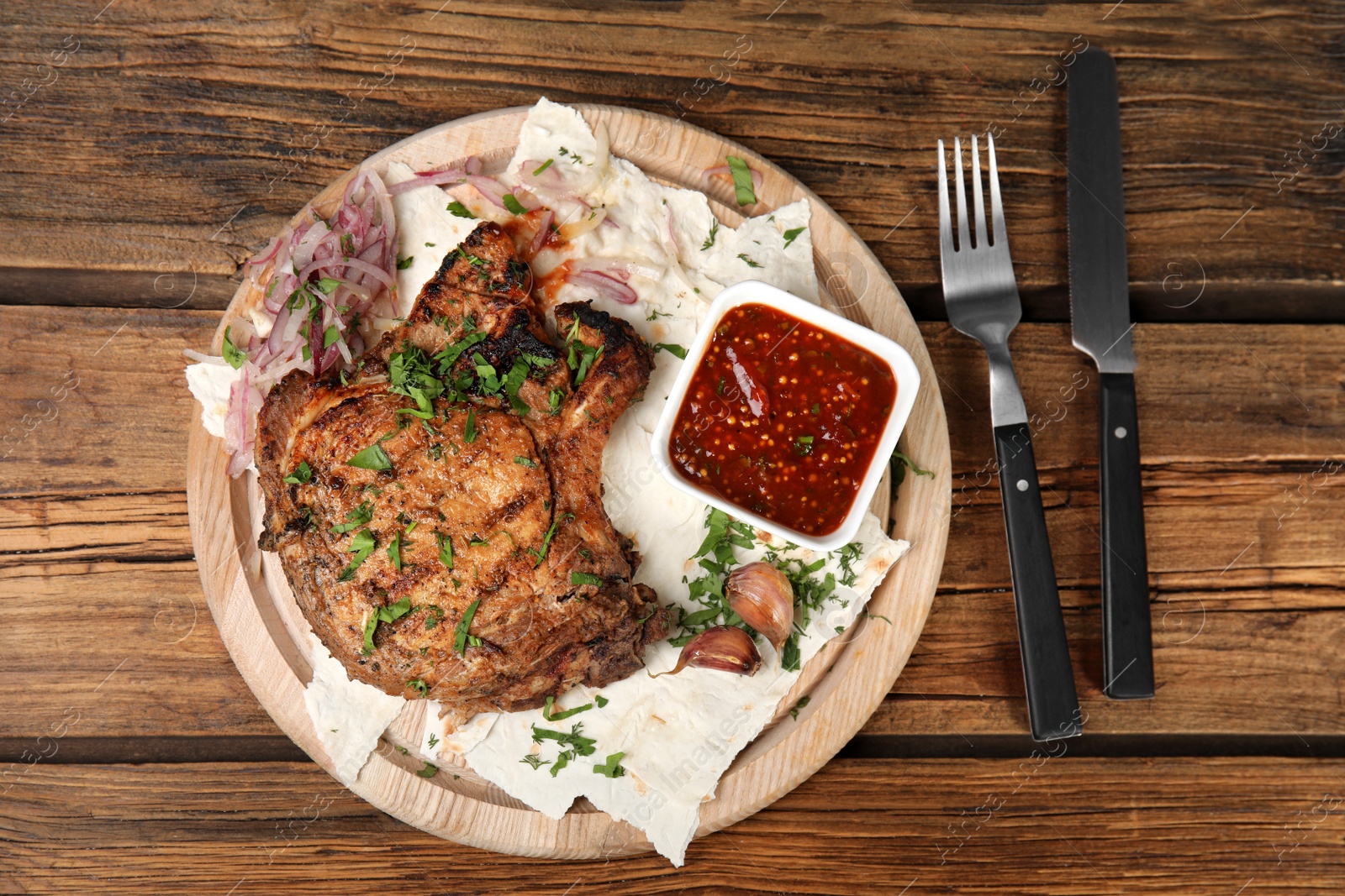 Photo of Delicious grilled pork chop served on wooden table, flat lay