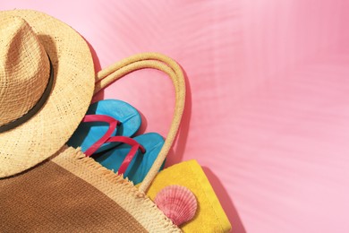 Photo of Bag with beach accessories on pink background, above view. Space for text