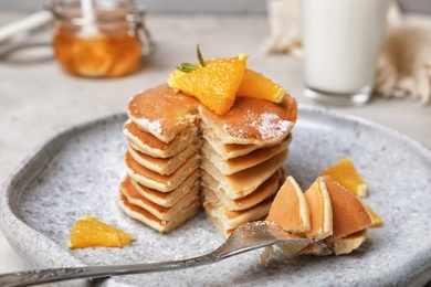 Tasty pancakes with orange on table