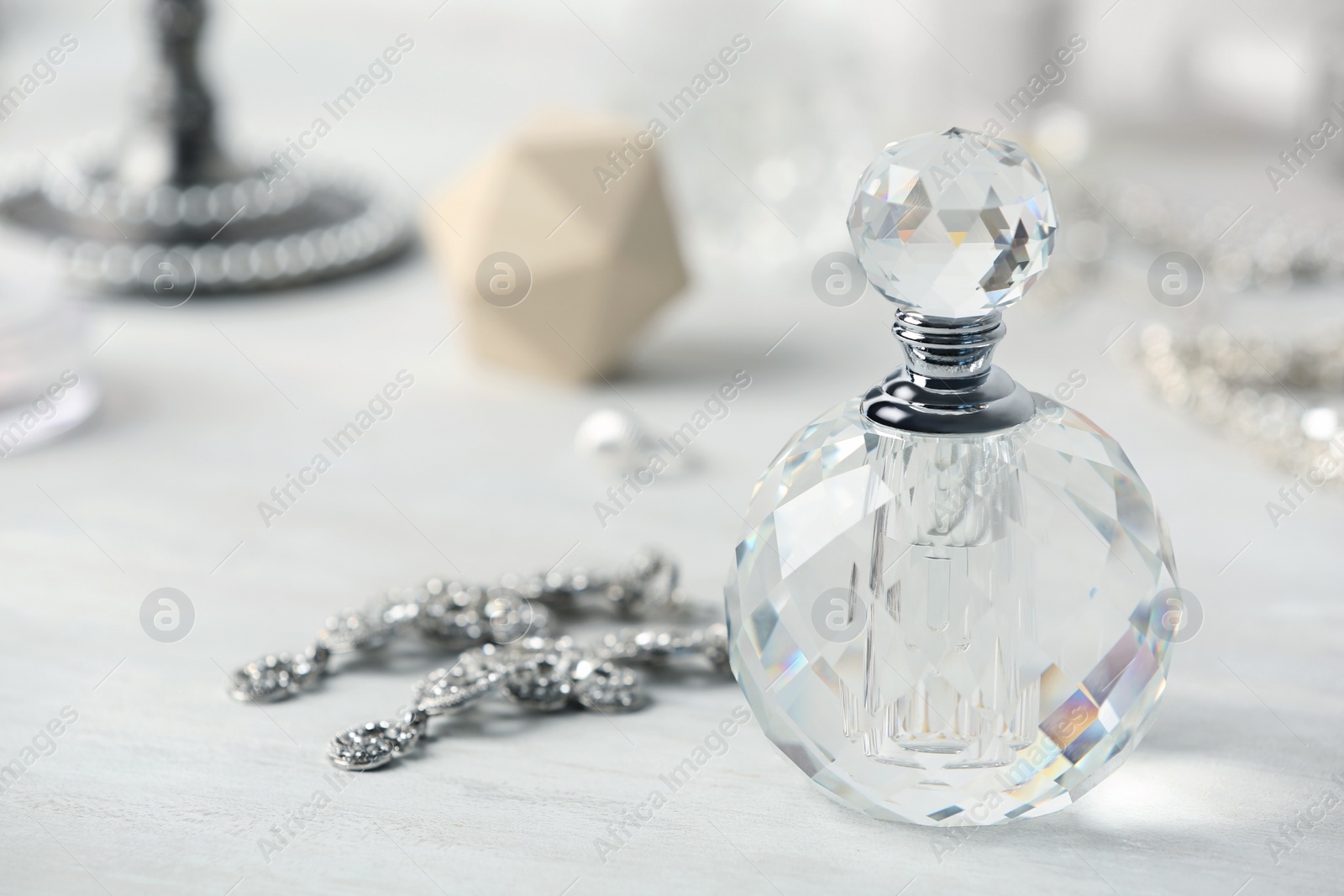 Photo of Perfume bottle and jewellery on dressing table. Space for text