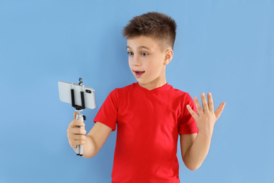 Photo of Emotional little blogger recording video on light blue background