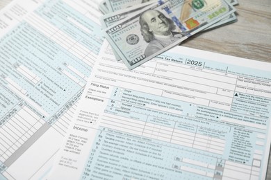 Photo of Payroll. Tax return forms and dollar banknotes on wooden table