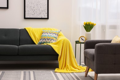 Spring atmosphere. Stylish living room interior with comfortable furniture and bouquet of beautiful yellow tulips