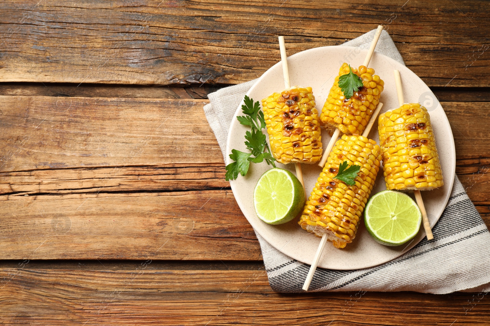 Photo of Tasty grilled corn on wooden table, top view. Space for text