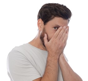 Embarrassed man covering face with hands on white background