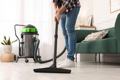Woman vacuuming floor in living room, closeup