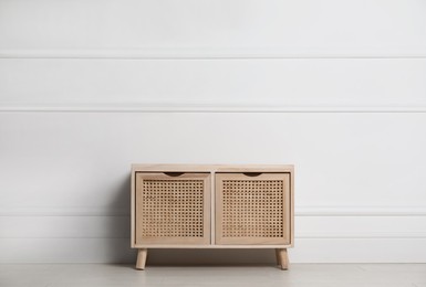 Wooden chest of drawers near white wall indoors