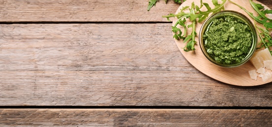 Top view of bowl with arugula pesto on wooden table, space for text. Banner design 