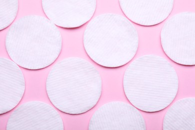 Soft clean cotton pads on pink background, flat lay