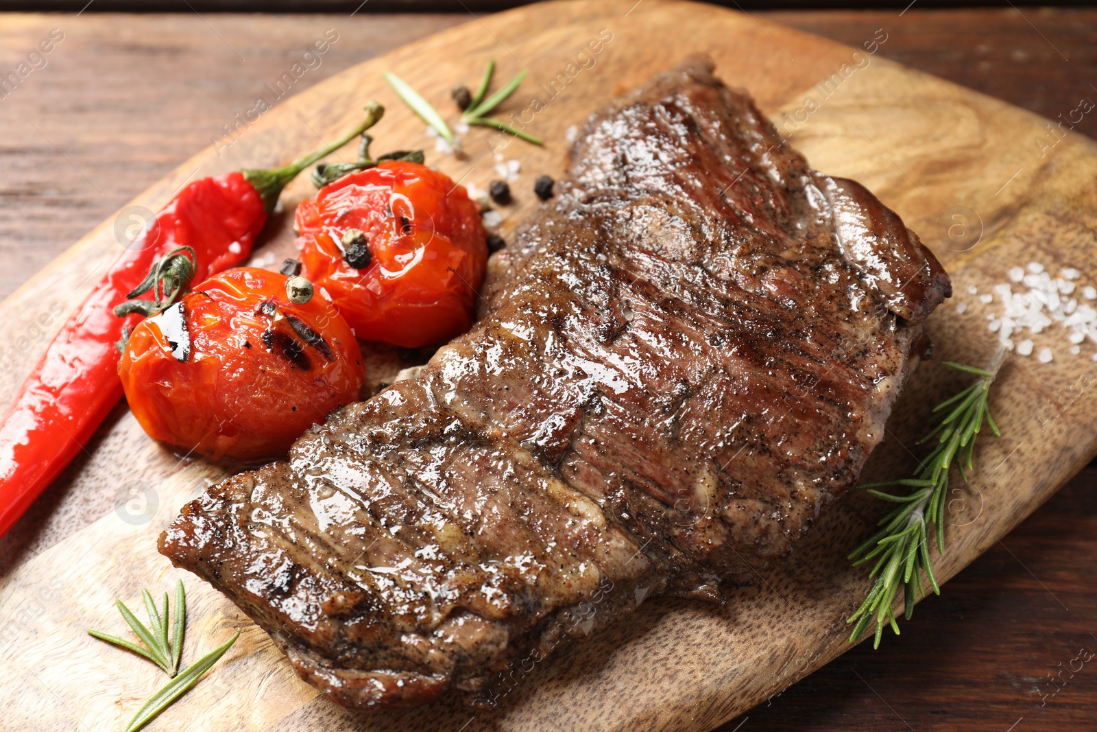 Photo of Delicious roasted beef meat, vegetables and spices on wooden table, closeup