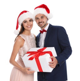 Lovely young couple in Santa hats with gift box on white background. Christmas celebration