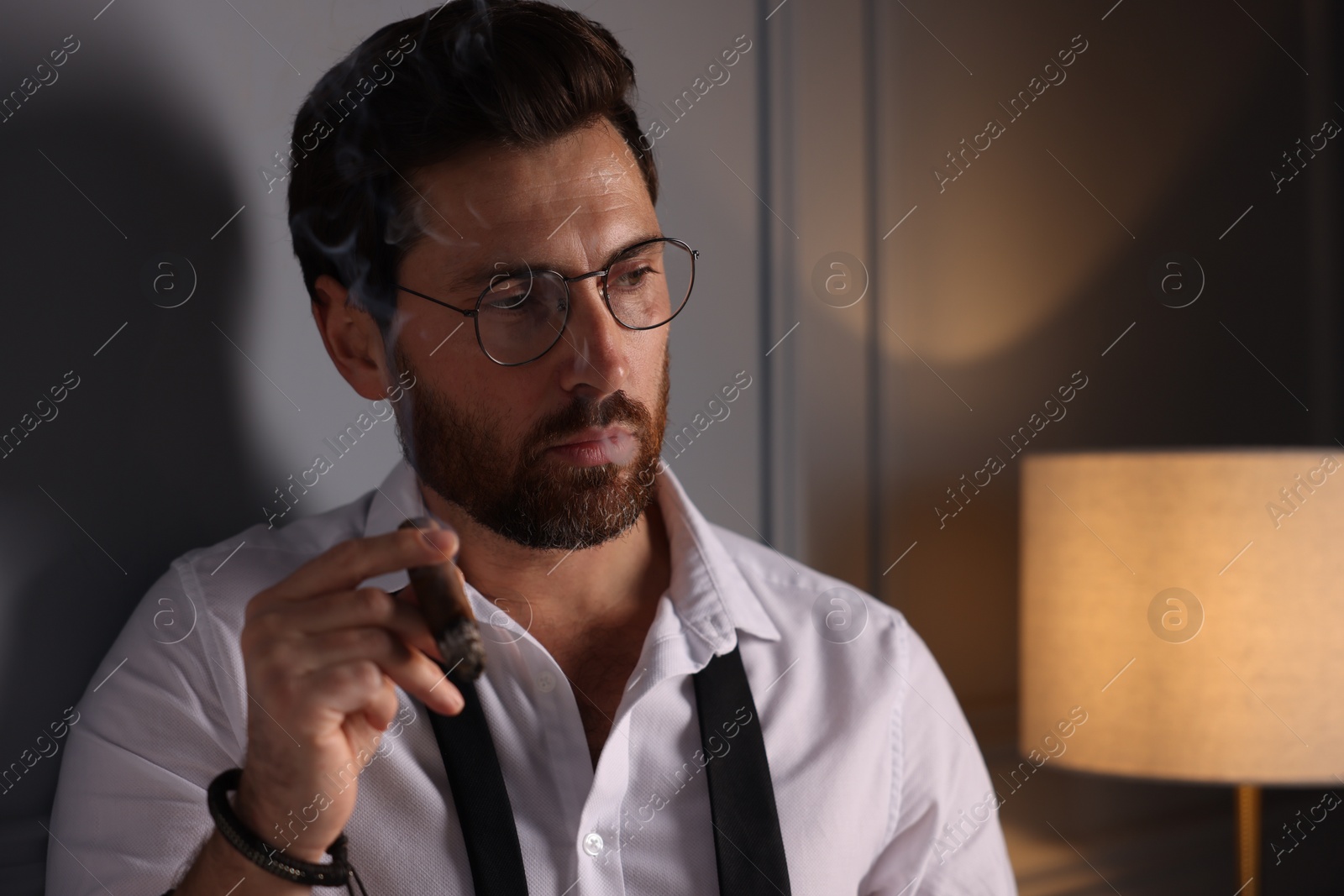 Photo of Thoughtful man smoking cigar at home. Space for text