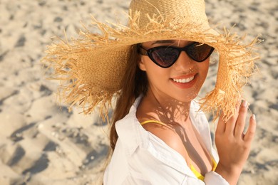 Photo of Young woman with sunglasses and hat at sandy beach. Sun protection care