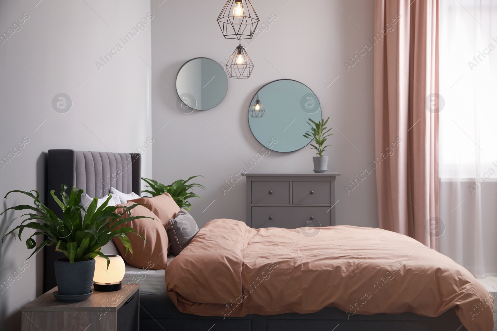 Photo of Stylish bedroom interior with comfortable bed and green houseplants