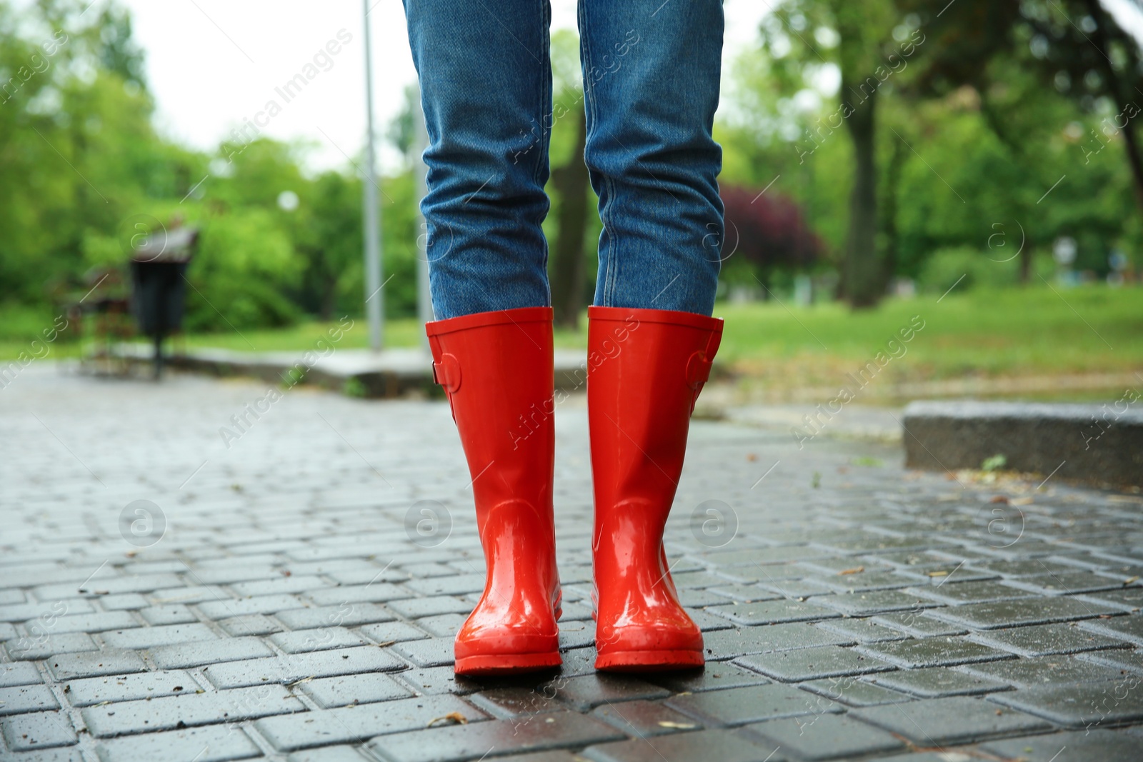 Photo of Woman with rubber boots in puddle, closeup. Rainy weather