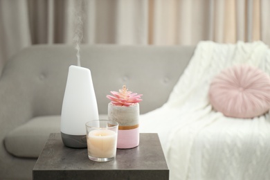 Aroma oil diffuser and candle on table in room