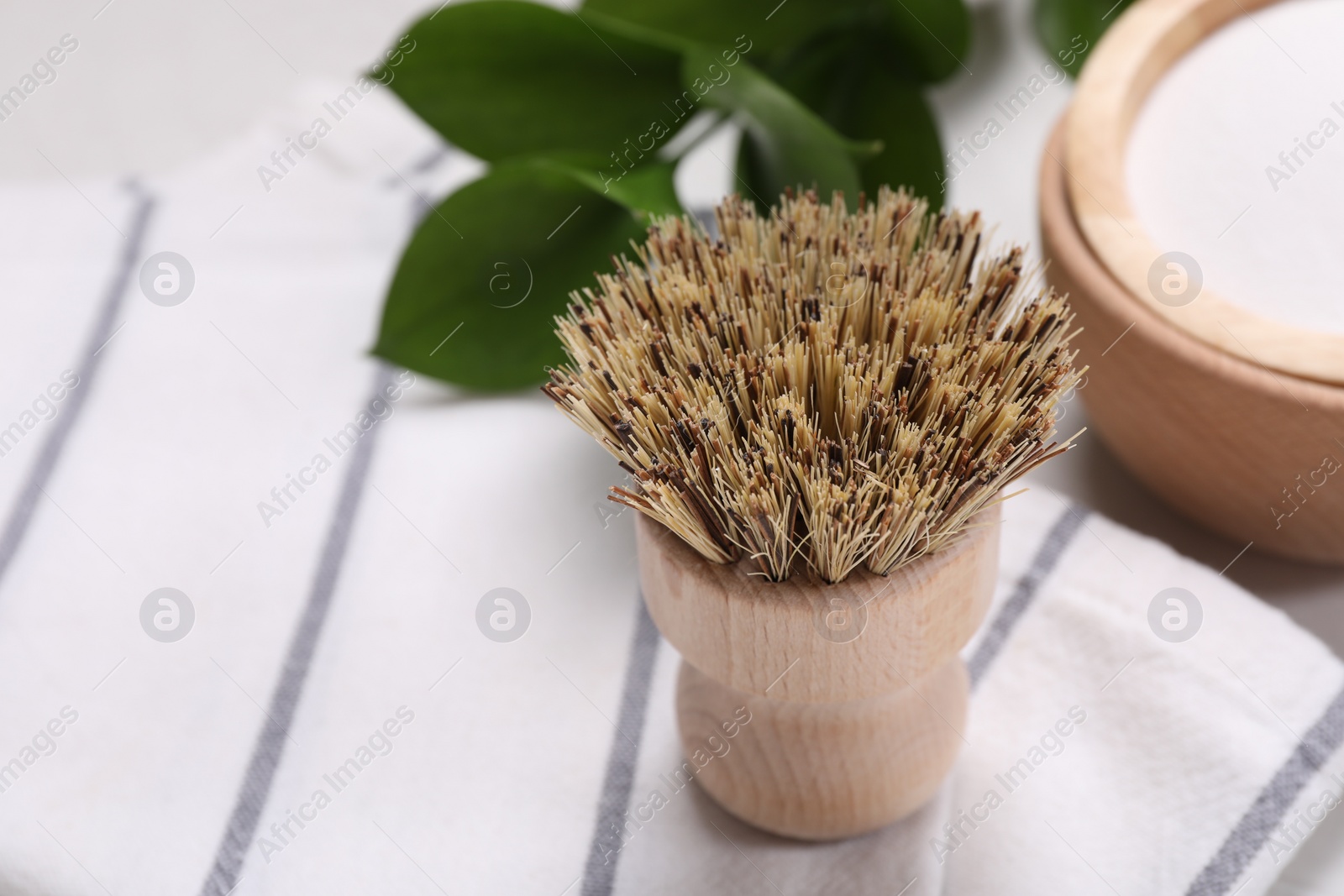 Photo of Cleaning brush, green leaves and baking soda on table, closeup. Space for text