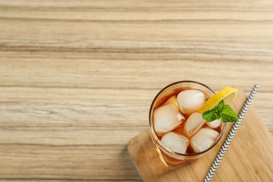 Photo of Glass of tasty ice tea with lemon on wooden table, top view. Space for text