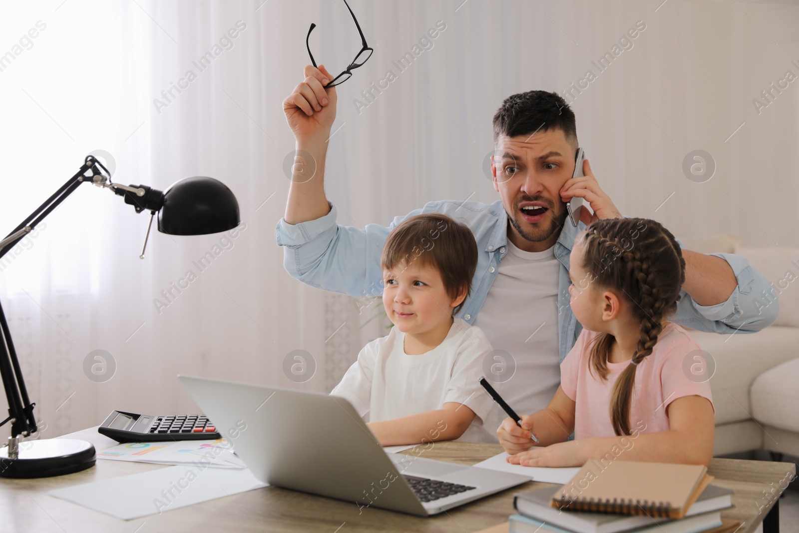 Photo of Overwhelmed man combining parenting and work at home