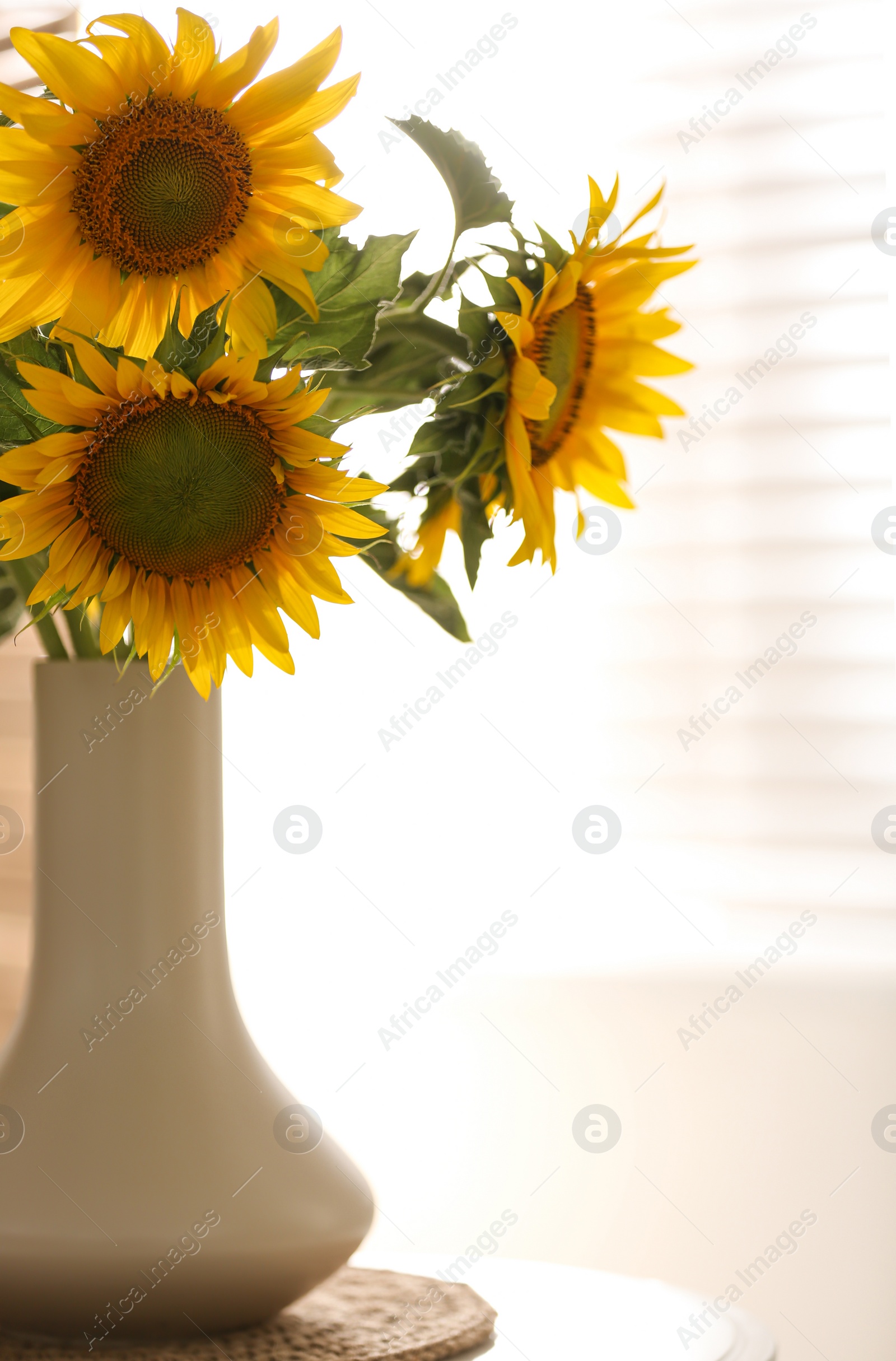 Photo of Vase with beautiful yellow sunflowers on table in room