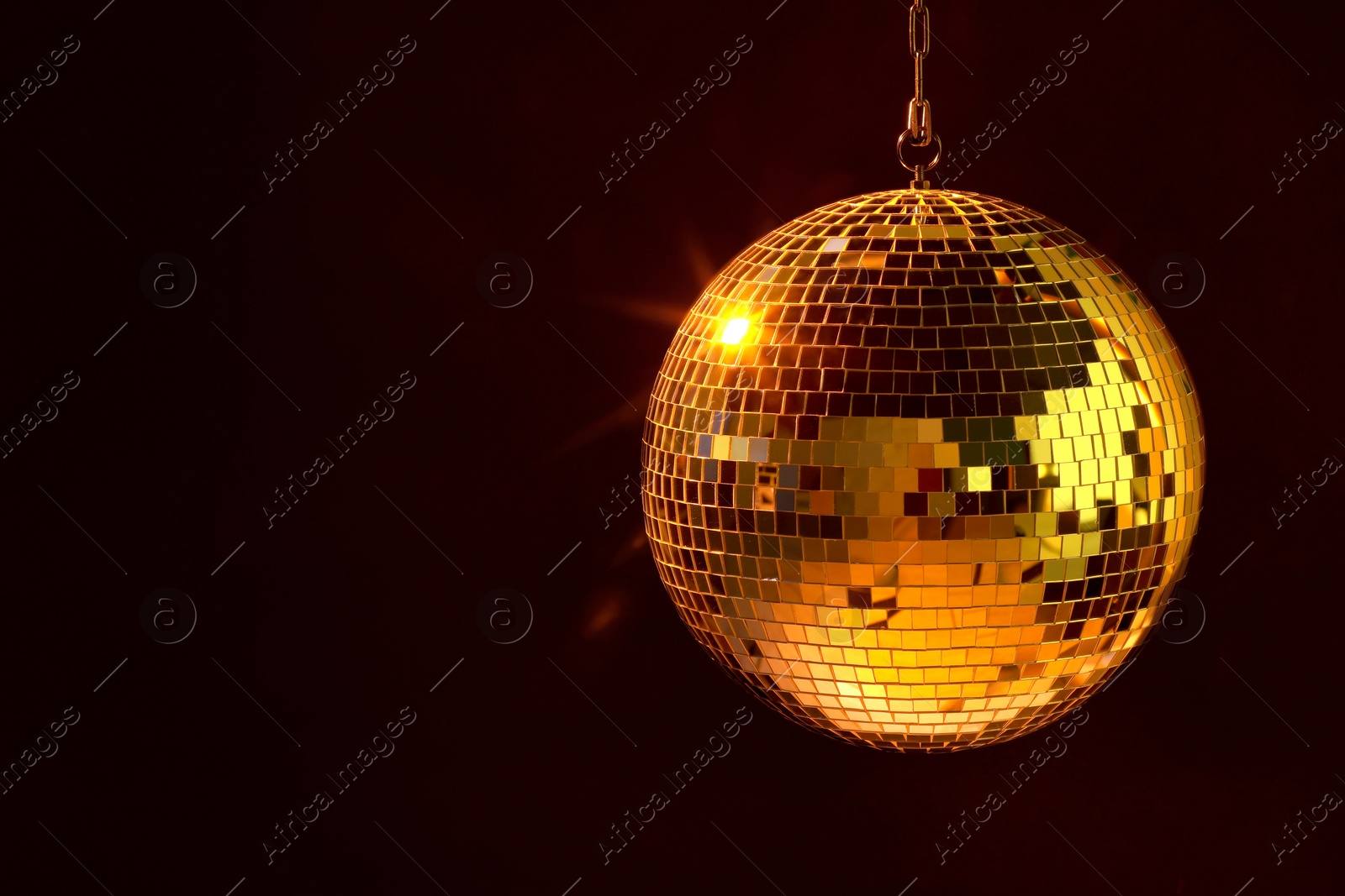 Photo of Shiny bright disco ball under orange light, space for text