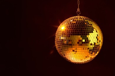 Photo of Shiny bright disco ball under orange light, space for text