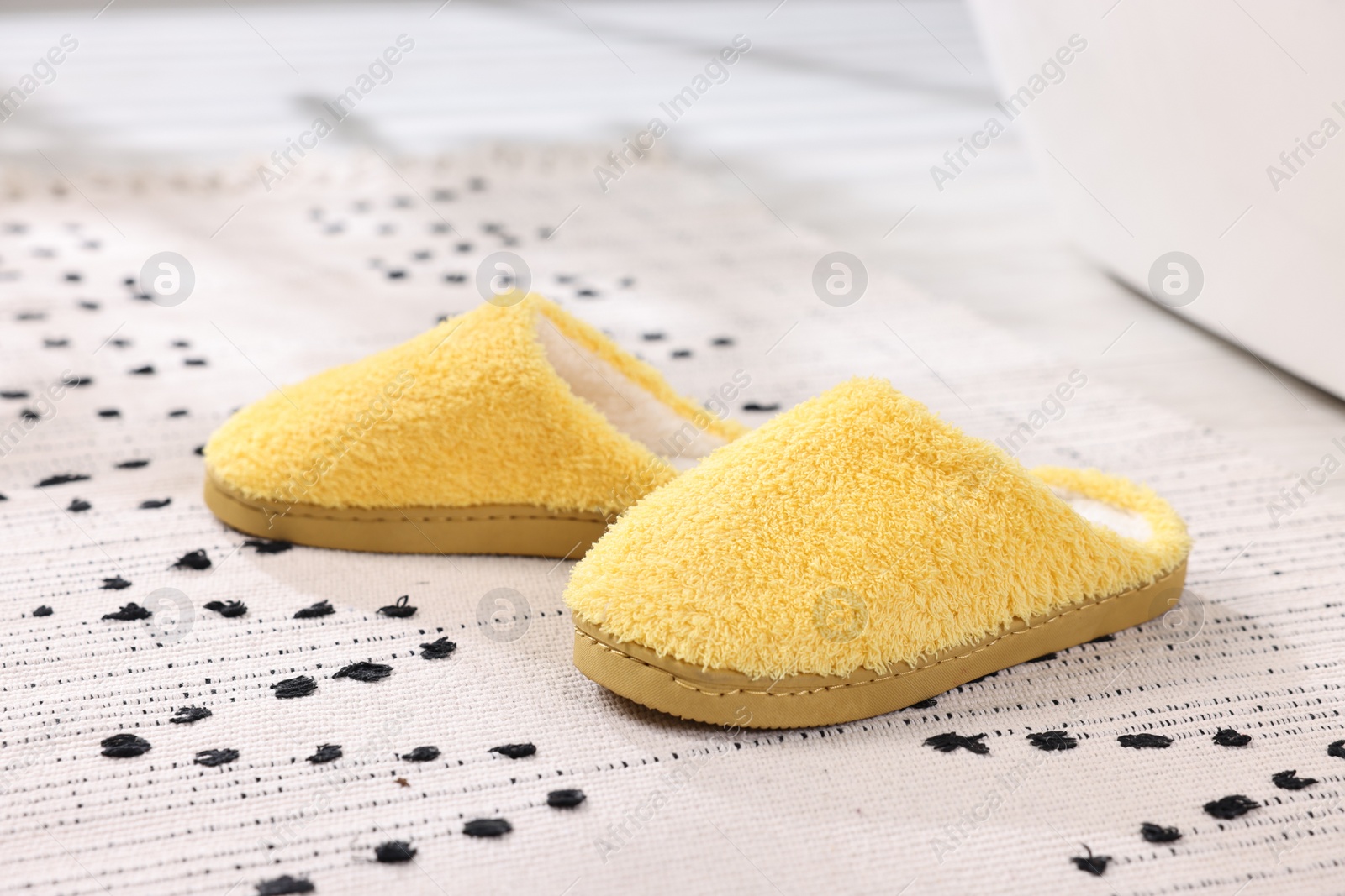 Photo of Yellow soft slippers on carpet at home, closeup