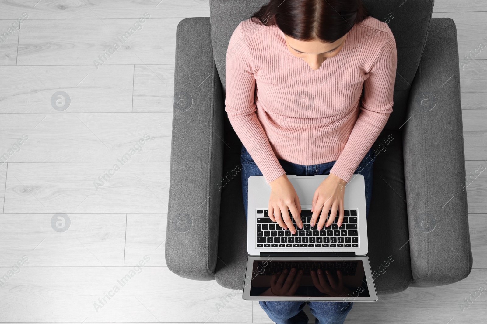 Photo of Woman working with laptop in armchair, top view. Space for text